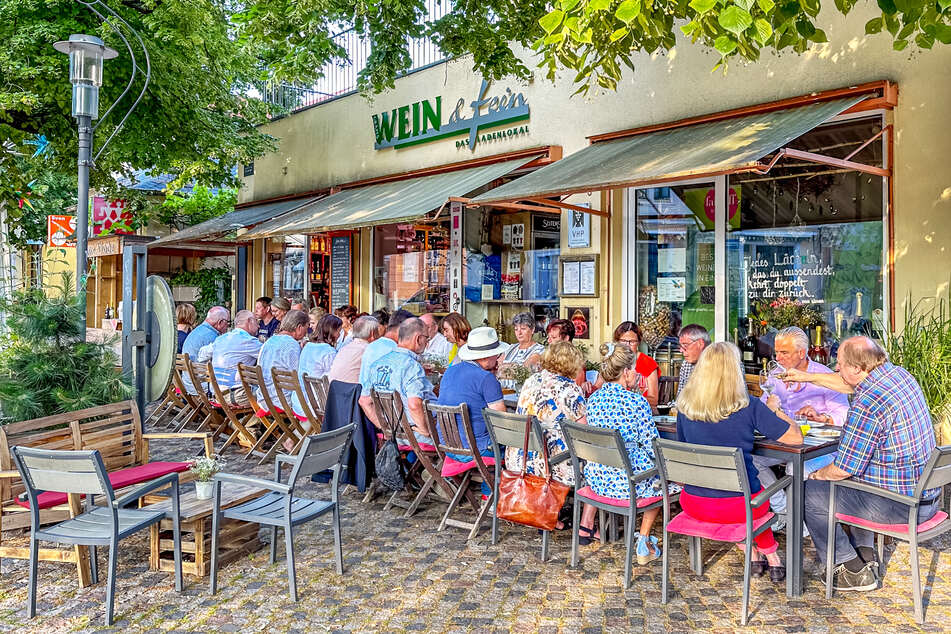 Bei "Wein auf der Hauptstraße" versammeln sich vor "Gräfe's Wein &amp; Fein" Genießer an einer großen Tafel.