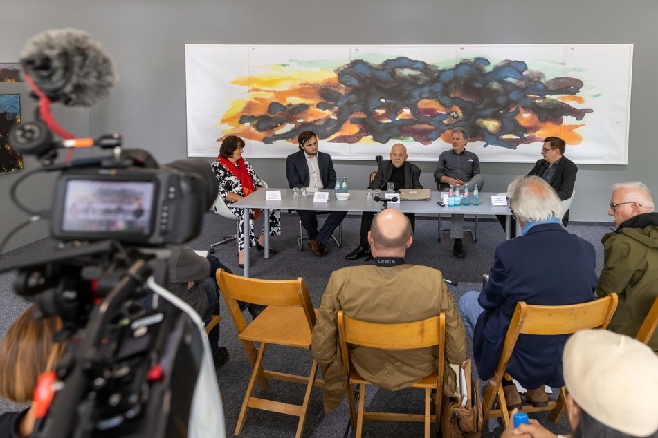 Max Uhlig (2.v.l.) bei der Pressekonferenz zur Ausstellungseröffnung in der Galerie Weise. Im Hintergrund ist ein Entwurf der Torgauer Aquarelle zu sehen.