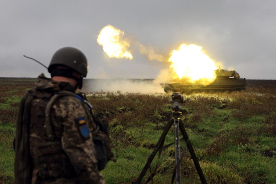 Ein ukrainischer Soldat beobachtet eine Panzerhaubitze 2S1 Gvozdika, die an der Frontlinie in der Region Donezk eine Granate abfeuert.