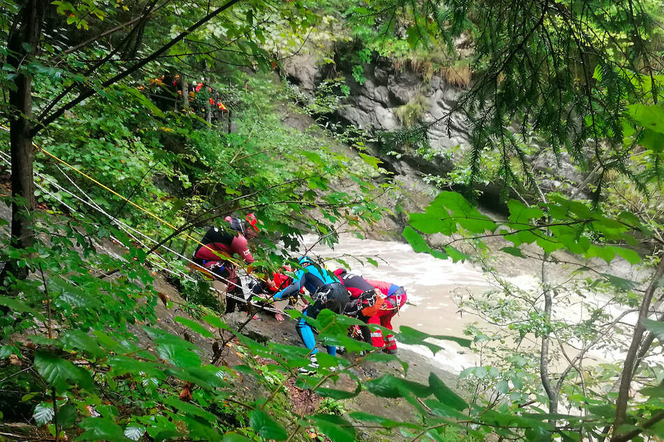 Retter arbeiten an einem Steilhang am Flussufer in der Starzlachklamm bei Sonthofen. Eine Gruppe war hier am Samstag von einer Sturzflut überrascht worden.