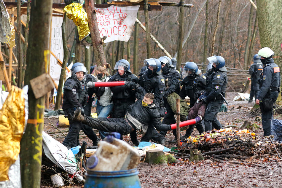 Polizisten tragen drei Aktivisten aus dem letzten verbliebenen Camp im Dannenröder Forst.