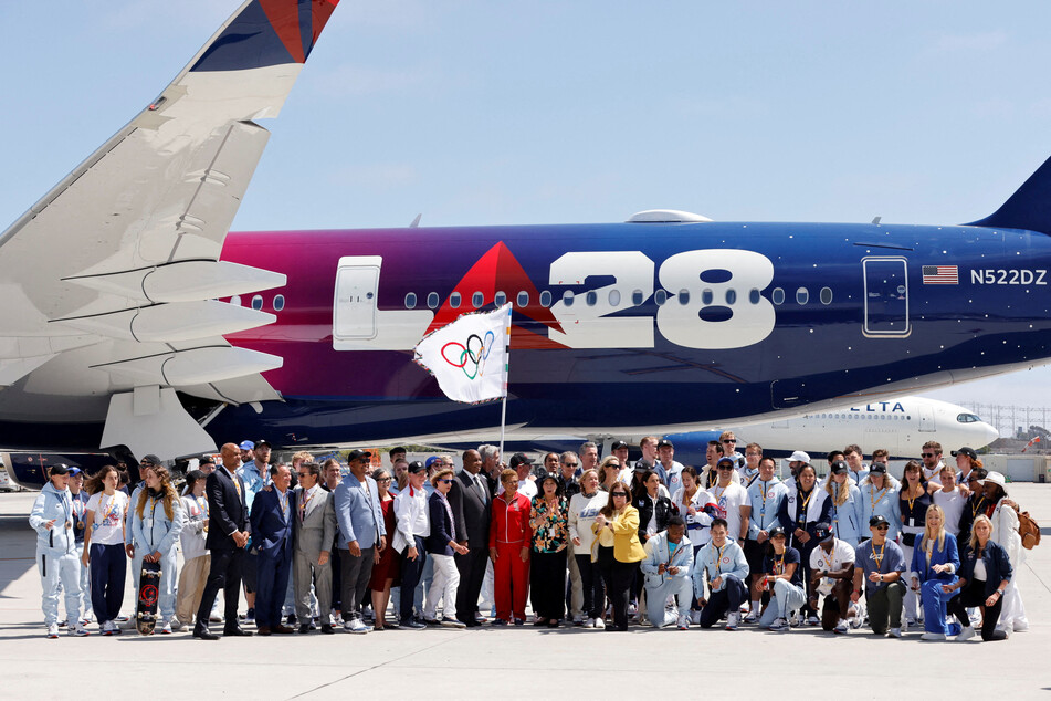 Members of LA28, local government officials, and Team USA athletes pose with the official Olympic flag as it arrives in Los Angeles.