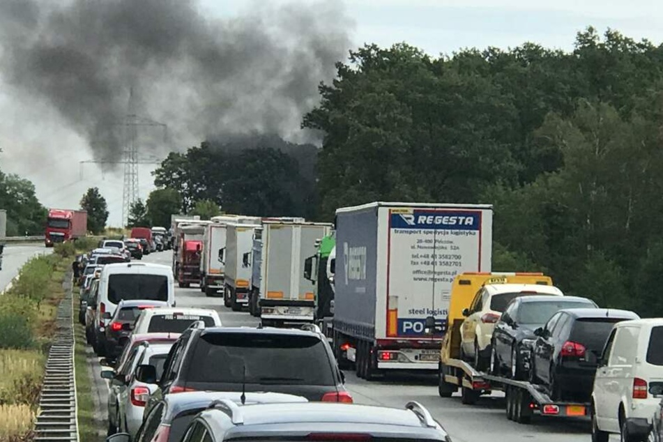 Eine schwarze Rauchwolke steht über der Fahrbahn.