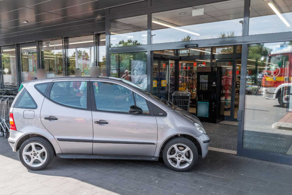 Das Auto steht vor dem Eingang eines Supermarktes.