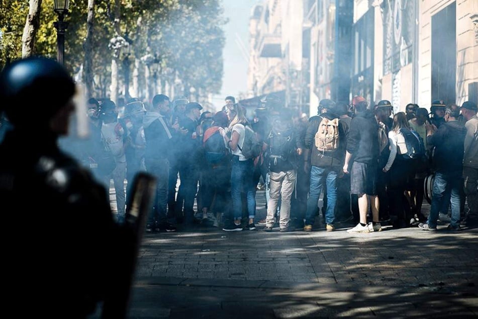 Demonstranten wenden sich ab, aus Schutz vor Tränengas, das von Bereitschaftspolizisten abgefeuert wurde.