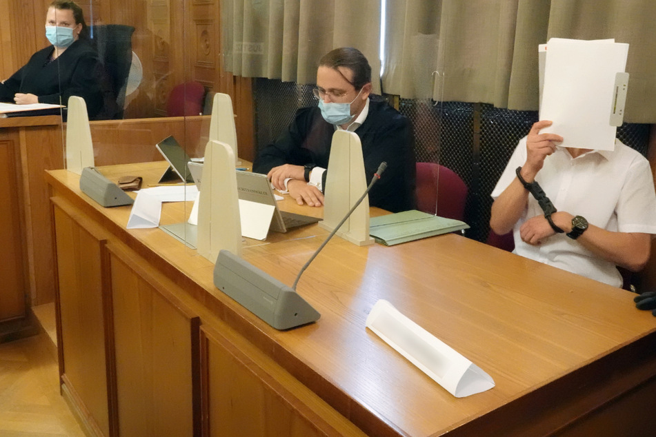 Im Prozess am Landgericht Tübingen um ein illegales Waffenlager verdeckt der Hauptangeklagte (r.) sein Gesicht. Der Hauptangeklagte soll in seiner Wohnung in Wildberg (Landkreis Calw) ein Waffenlager aufgebaut haben.