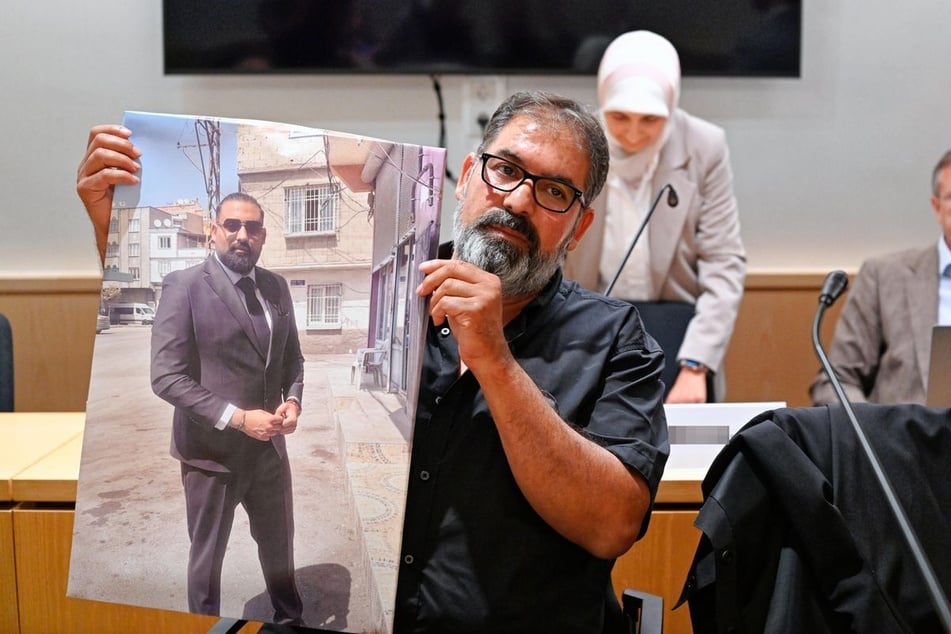 Erdal Calar, Vater des getöteten Zugbegleiters Serkan Calar, hält im Verhandlungssaal des Landgerichts ein Bild des Opfers in den Händen.