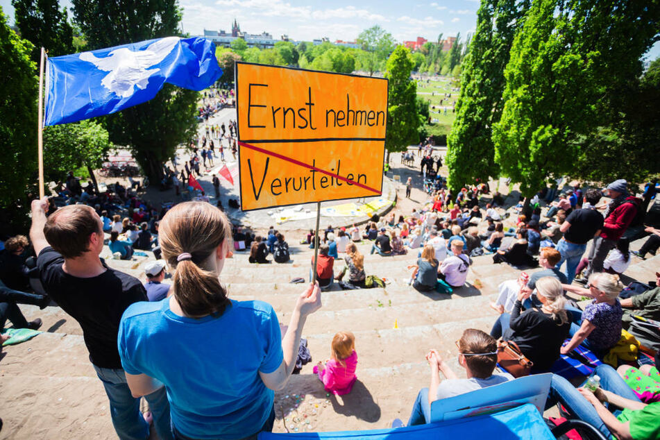 Demonstranten sitzen bei einer Kundgebung gegen die Corona-Maßnahmen im Berliner Mauerpark. Laut Polizei hat es bei den für Montag angemeldeten Demonstrationen bislang keine Zwischenfälle gegeben.