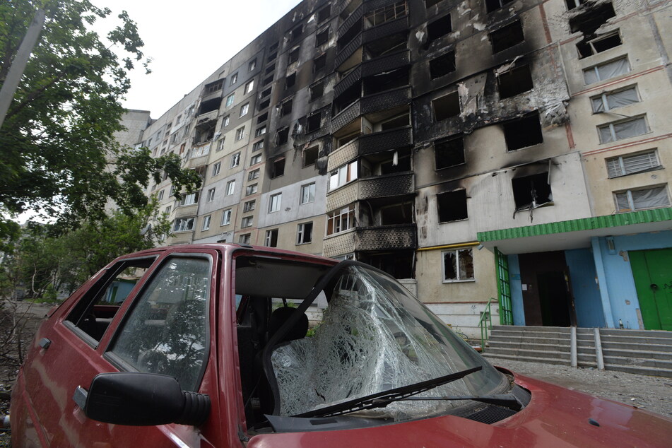 Ein zerstörtes Auto steht vor einem beschädigtem Gebäude in Charkiw. Recherchen von Amnesty International zufolge sollen russische Truppen durch den Einsatz von Streumunition zahlreiche Zivilisten getötet haben.
