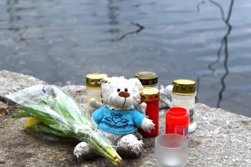 Blumen, Kerzen und ein Plüschtier liegen an dem Weiher in der Nähe des Fundortes der Babyleiche. (Archivbild)