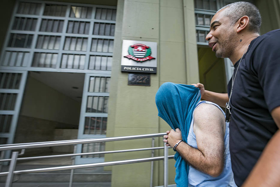 Ein Polizist führt in Sao Paulo einen festgenommenen Verdächtigen ab.