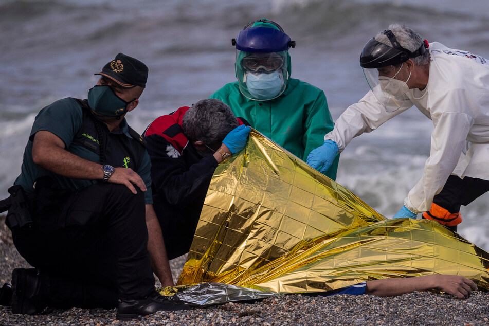 Medizinisches Personal und Polizisten untersuchen die Leiche eines jungen Mannes, der aus dem Wasser nahe der Grenze zwischen Marokko und Spaniens nordafrikanischer Exklave Ceuta geborgen wurde.