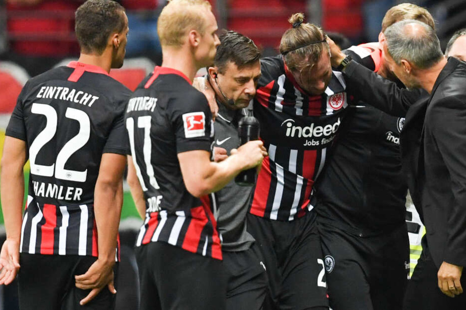Frankfurts Cheftrainer Adi Hütter (r.), Timothy Chandler (l) und Sebastian Rode (2.v.l.) stehen beim verletzten Marco Russ (M).