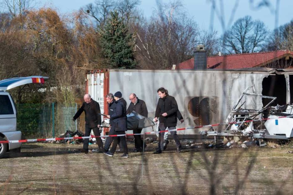 Ermittler der Polizei und Bestatter transportieren eine der Leichen ab.