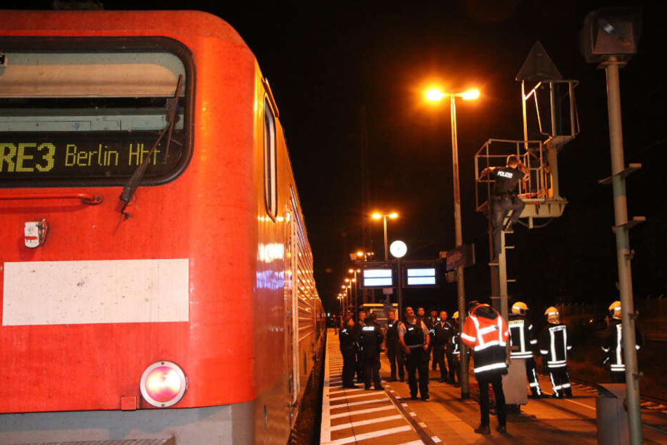 Ein Polizist klettert den Oberleitungsmast hoch.