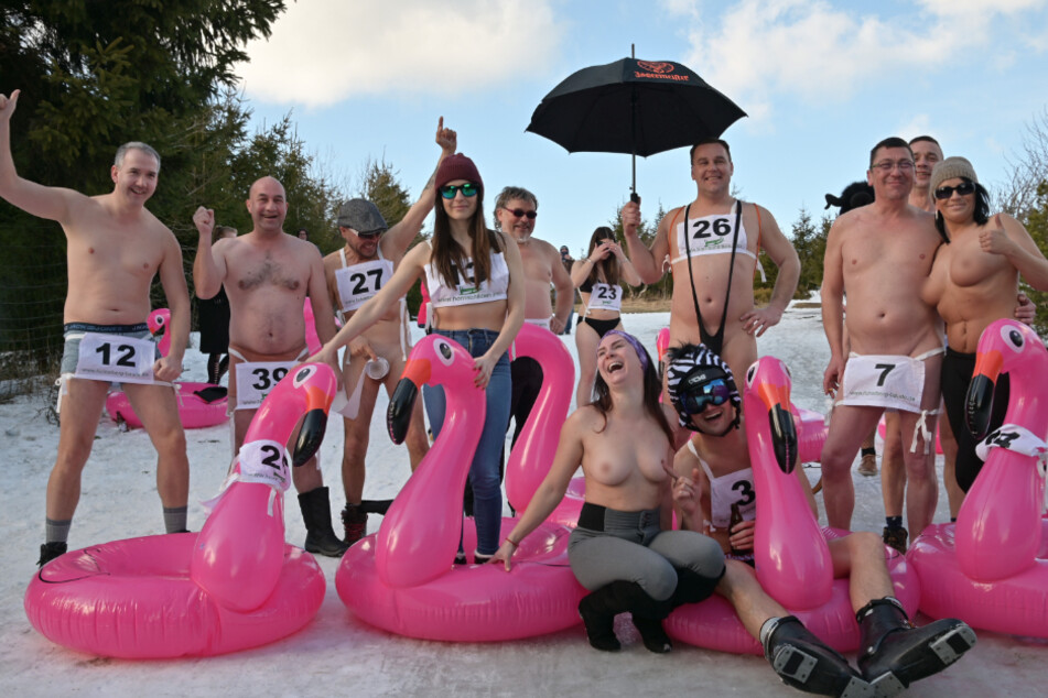 Teilnehmer des Nacktrodelns mit ihren lila Schlitten-Flamingos.