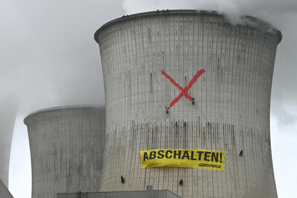 Aktivisten der Umweltorganisation Greenpeace hängen ein Banner mit der Aufschrift "Abschalten" an einem Kühlturm des Braunkohlekraftwerks Neurath auf.