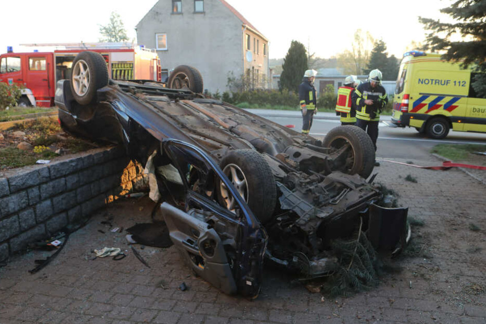 Die Rettungskräfte am völlig zerstörten Auto.