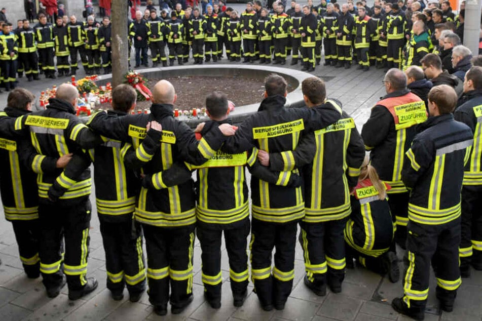 Feuerwehrleute trauern am Augsburger Königsplatz, nachdem ein 49-Jähriger hier attackiert und später verstorben war.
