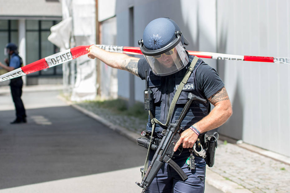 Ein mit einer Maschinenpistole bewaffneter Polizist bewegt sich durch eine Absperrung am Anger. Der Einsatz von ihm und seinen Kollegen könnte nun richtig teuer werden.
