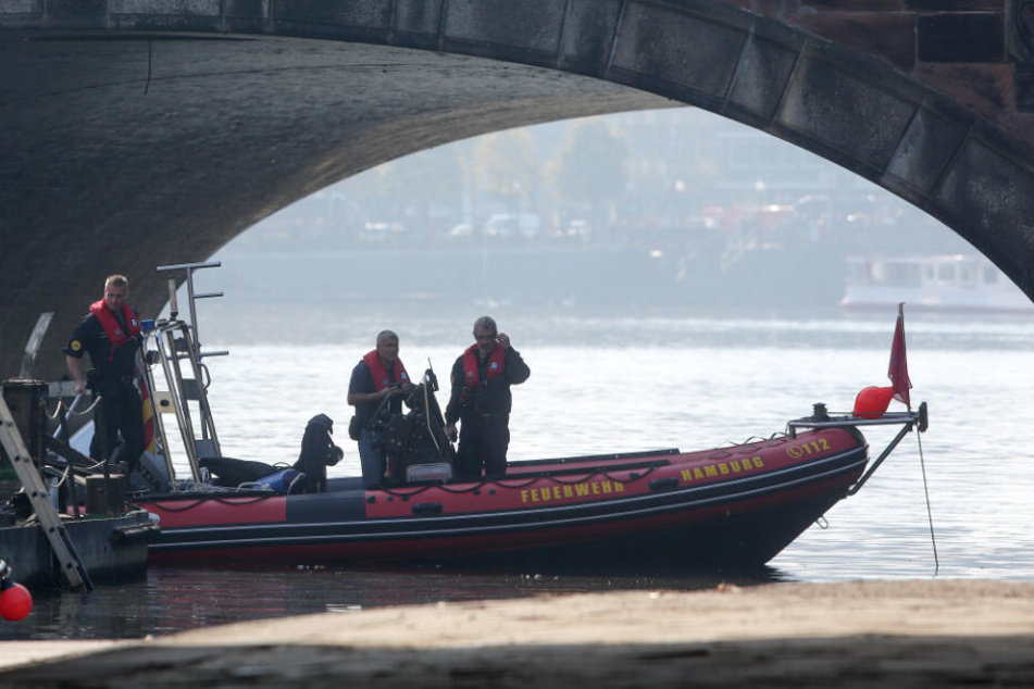 Einsatzkräfte des Kampfmittelräumdienstes stehen bei der Bergung einer Weltkriegsgranate im Bereich der Lombardsbrücke in einem Boot. (Archivbild)