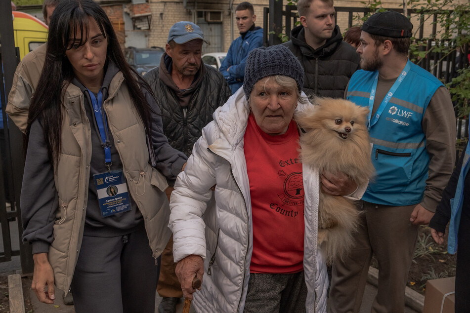 Olga Garmash (c.), 68-years-old, an evacuee from the village of Lyptsi, arrives with her dog at an evacuation point in Kharkiv, on May 11.