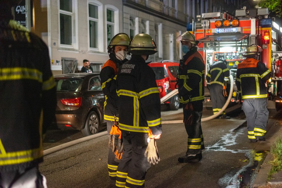 Rettungskräfte der Feuerwehr stehen am Einsatzort in der Hopfenstraße.