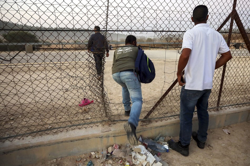 Palästinensische Arbeiter überqueren illegal aus dem Westjordanland durch ein Loch in einem Zaun die Grenze nach Israel.