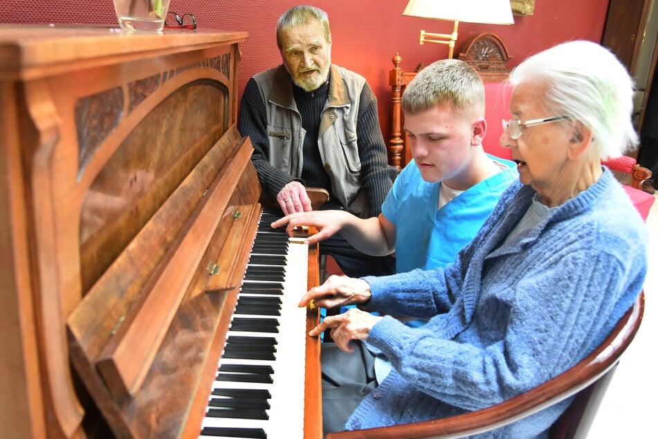 Eine Rentnerin spielt mit den beiden Bundesfreiwilligen, dem 80 Jahren alten Manfred Duncker (l) und dem 17-jährigen Lasse Masthoff am Klavier.