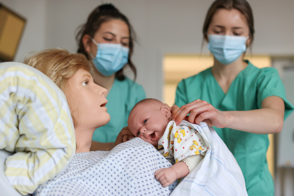 Zwei Studentinnen üben den erstmaligen Mutter-Kind-Kontakt nach der Geburt an einer Übungspuppe in einer Klinik in Leipzig.