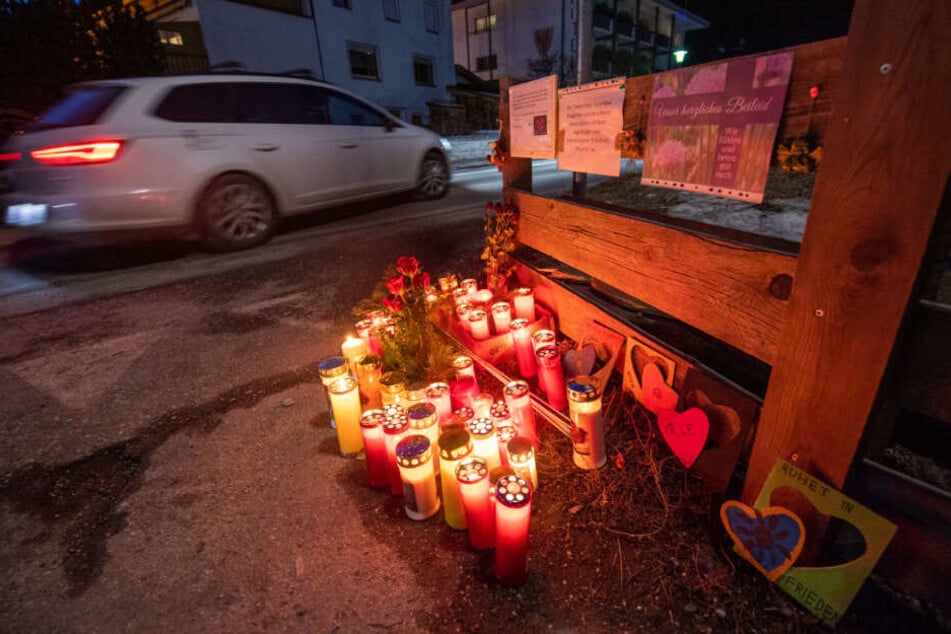 Blumen, Kerzen und Gedenkschmuck stehen und liegen am Ort des Unfalls und leuchten nach Sonnenuntergang.