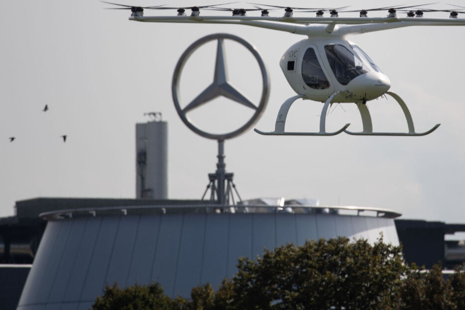 Ein sogenannter Volocopter fliegt in Stuttgart vor einem Gebäude des Autobauers Daimler.