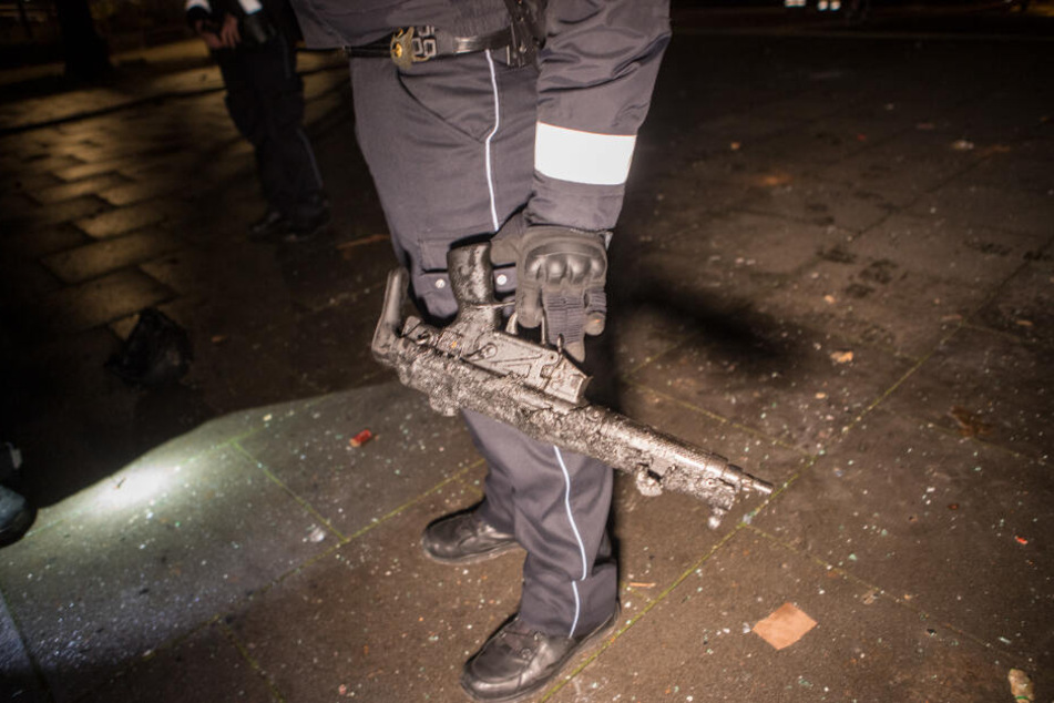 Ein Polizist hält eine geschmolzene Maschinenpistole in der Hand.