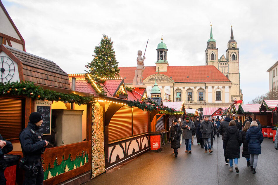 Bürger laufen am Sonntag zwischen den geschlossenen Buden des Magdeburger Weihnachtsmarkts.