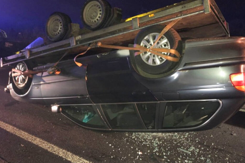 Der transportierte BMW liegt mitsamt Hänger auf dem Dach.