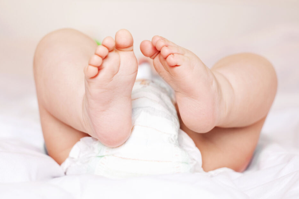 Ein Baby liegt auf einer Decke.