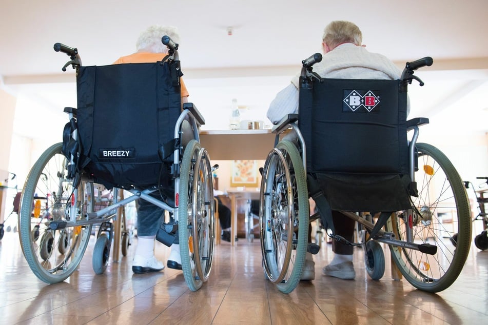 Zwei Frauen sitzen in einem Pflegeheim in ihren Rollstühlen nebeneinander.