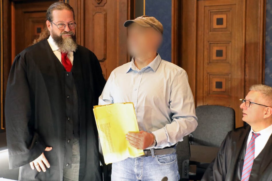 Der Angeklagte (Mitte) steht zwischen seinen beiden Verteidigern.