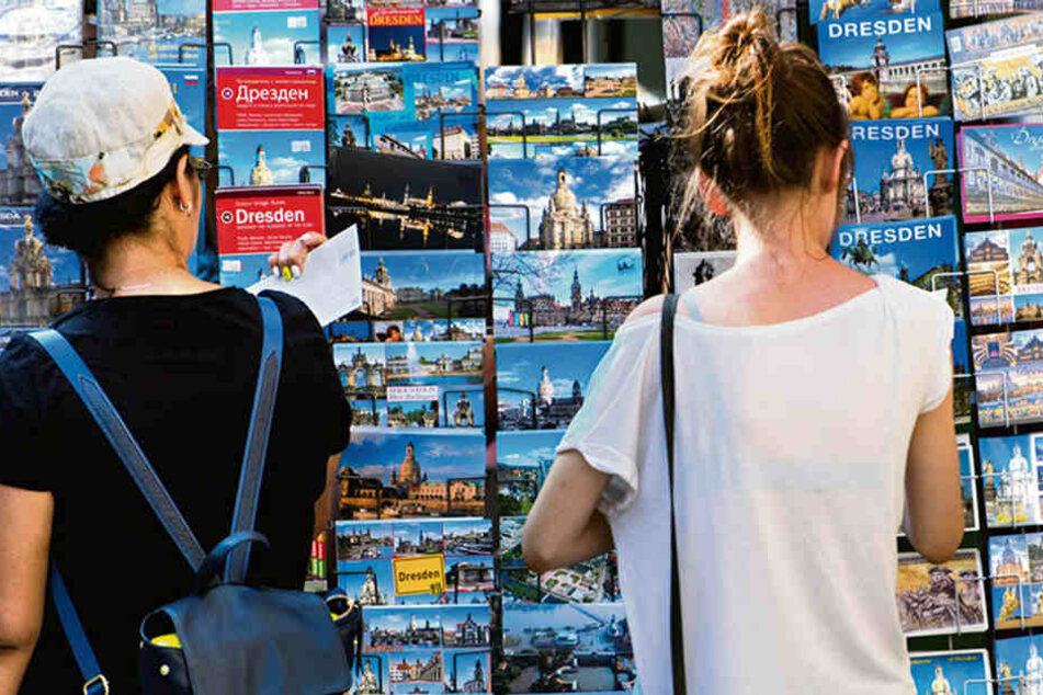 Zwei Frauen sehen sich Postkarten an einem Stand in der Dresdner Altstadt an.