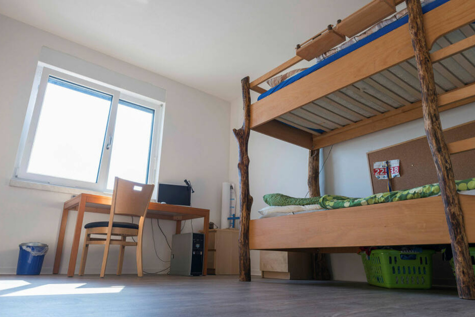 Das helle Zimmer eines Häftlings: modernes Doppelstockbett, Schreibtisch, großes Fenster.