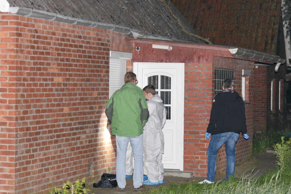 Polizeibeamte untersuchen eine Eingangstür des Hauses, in dem die 31-Jährige tot aufgefunden wurde.