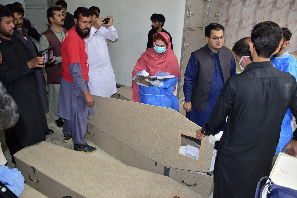 Ärzte und anderes Personal untersuchen die Leiche einer Person, die von Bewaffneten getötet wurde.