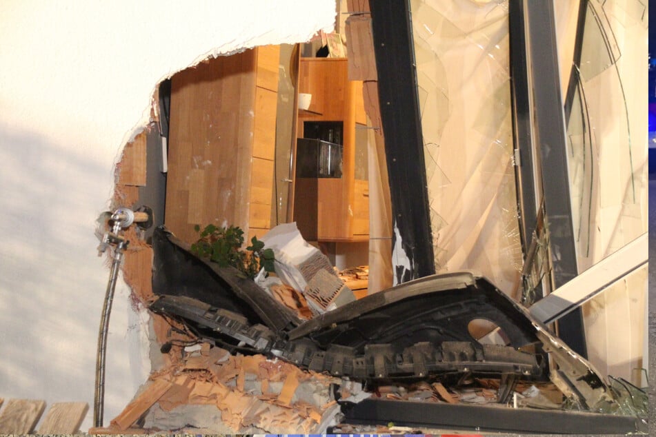 In der Hauswand des Nachbarn klafft ein großes Loch, sodass man bis auf die Wohnzimmereinrichtung blicken kann.