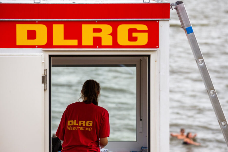 Eine Rettungsschwimmerin der DLRG (Deutsche Lebens-Rettungs-Gesellschaft) steht vor dem Fenster eines Wachturms.
