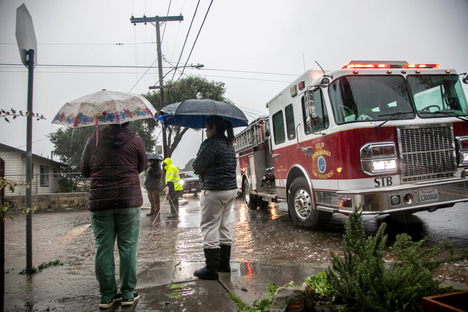 Residents stand near a fire truck on a flooded street in east Santa Barbara, California.