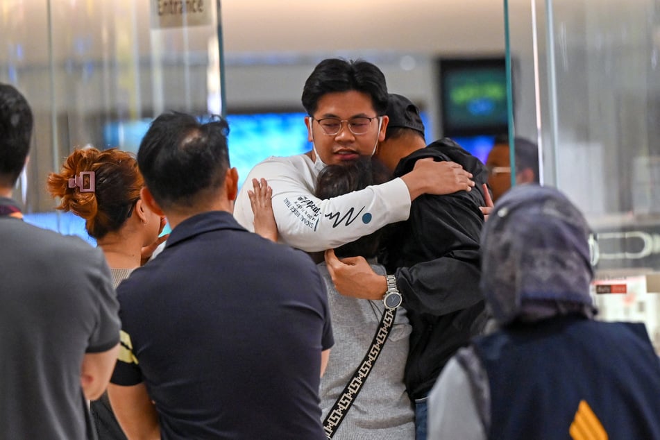 Nach der Ankunft am Airport Singapur-Changi werden Passagiere des Unglücksfluges von Angehörigen empfangen.