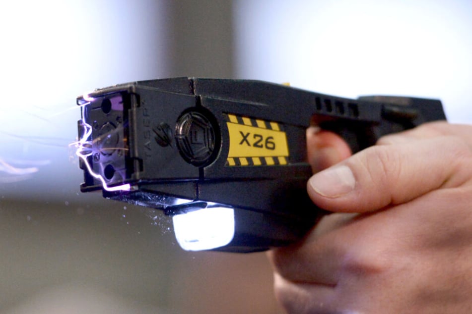 Ein Taser verschiesst Pfeile, die über dünne Drähte mit der Waffe verbunden sind und über die Strom mit etwa 50.000 Volt fließt.