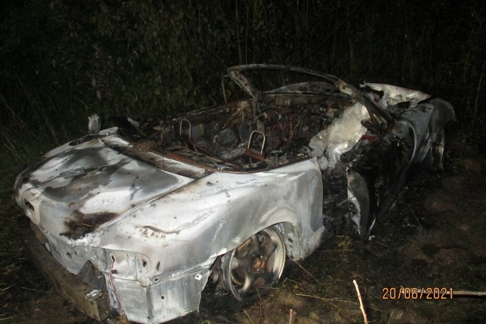 Nach einem Unfall war der ursprünglich grüne Mazda MX-5 im hohen Gras abseits der Straße abgestellt worden und brannte vollständig aus.