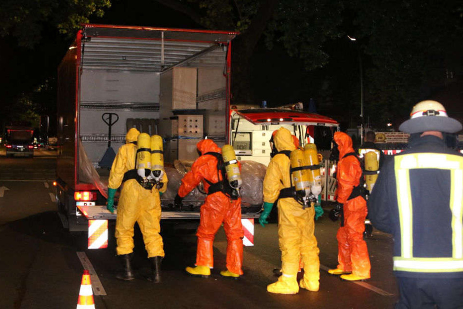Feuerwehrleute in Schutzanzügen bringen die Leiche zum Lkw.