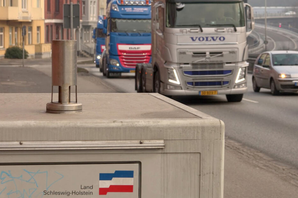 Fahrzeuge fahren an einer Luftmessstation am Theoder-Heuss-Ring in Kiel vorbei.